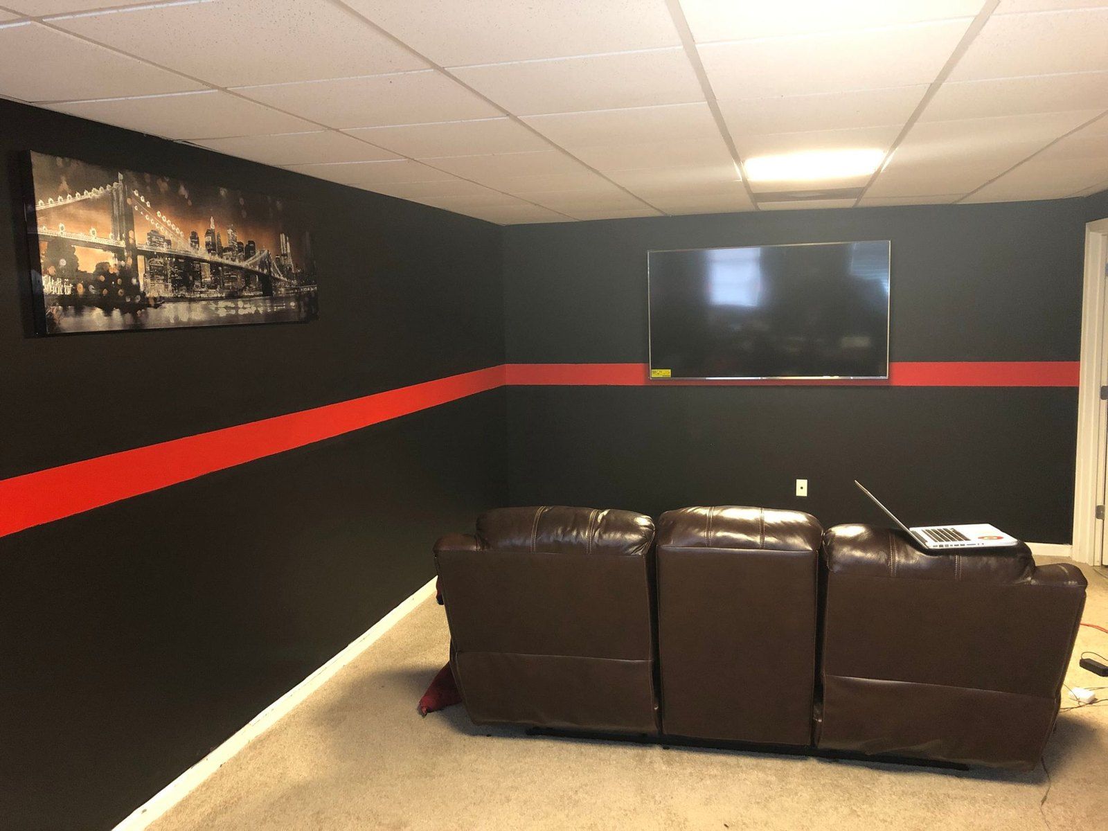 Finished media room with dark walls, accent stripe and theater seating