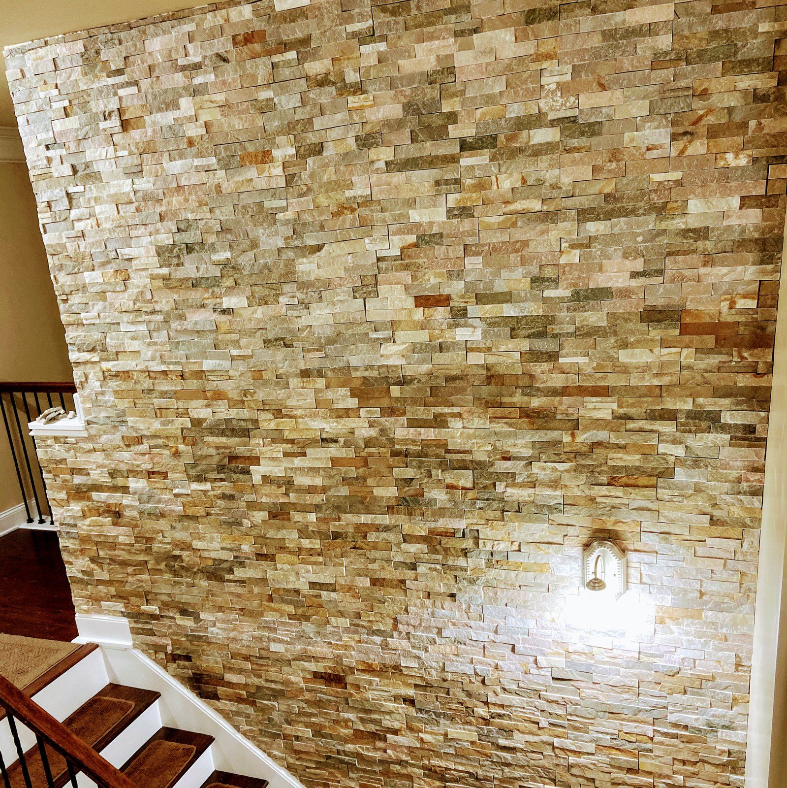 Stacked stone accent wall installed beside a staircase